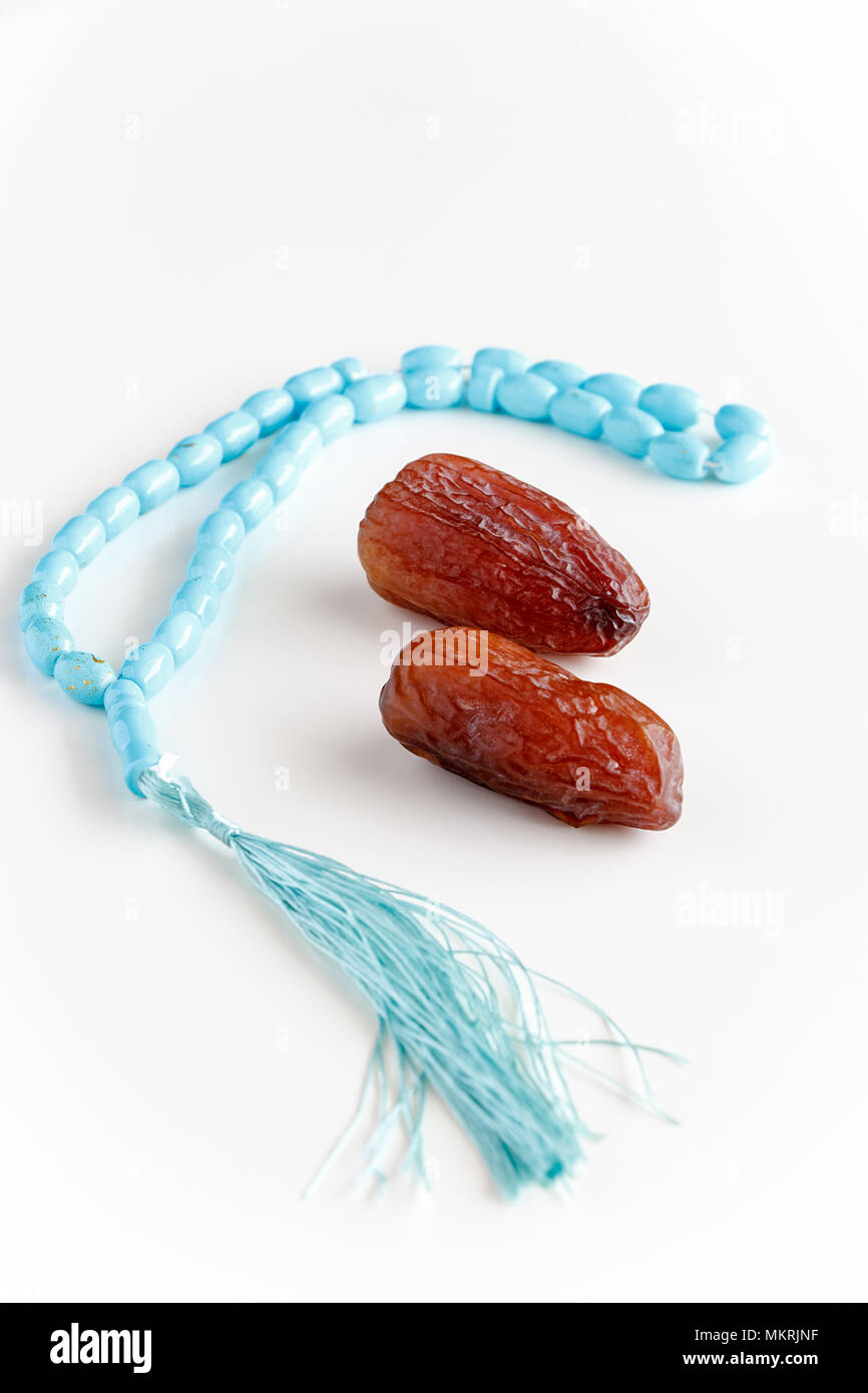 Glass of water, Organic dates Medjool and rosary. Concept breaking fast. White background. Selective focus. Copy space. Stock Photo