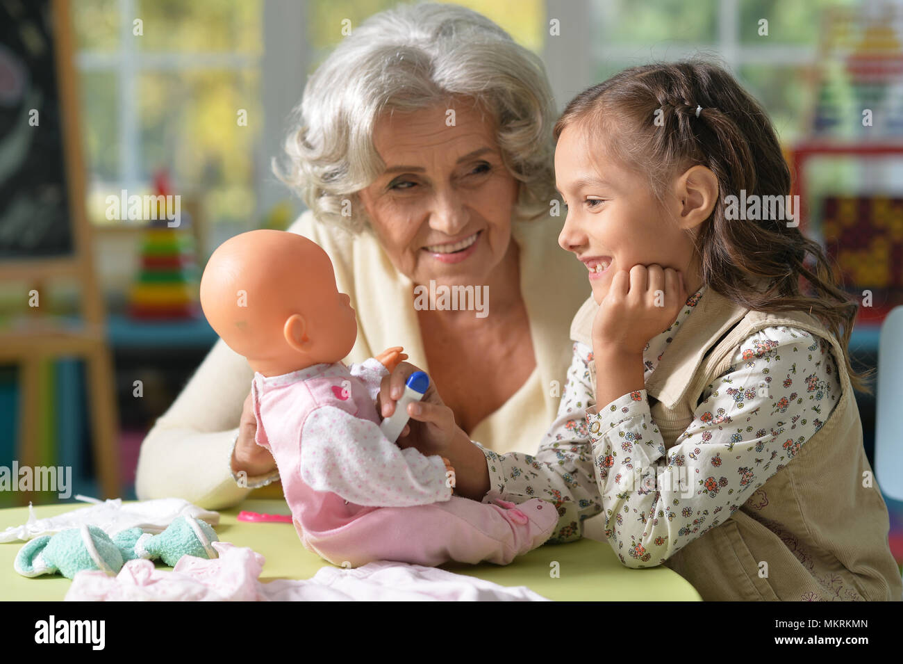 Portrait of grandmother and child play with baby doll Stock Photo