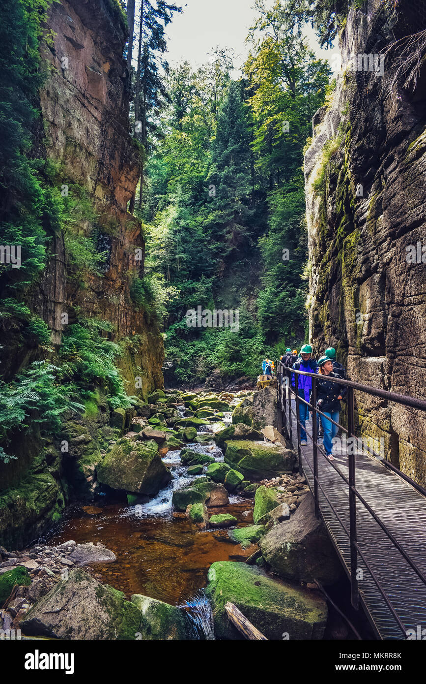 Szklarska Poreba / Poland - 08.10.2016: Tourists walking between narrow and  tall rocky walls next to the creek in the mountains. Stock Photo