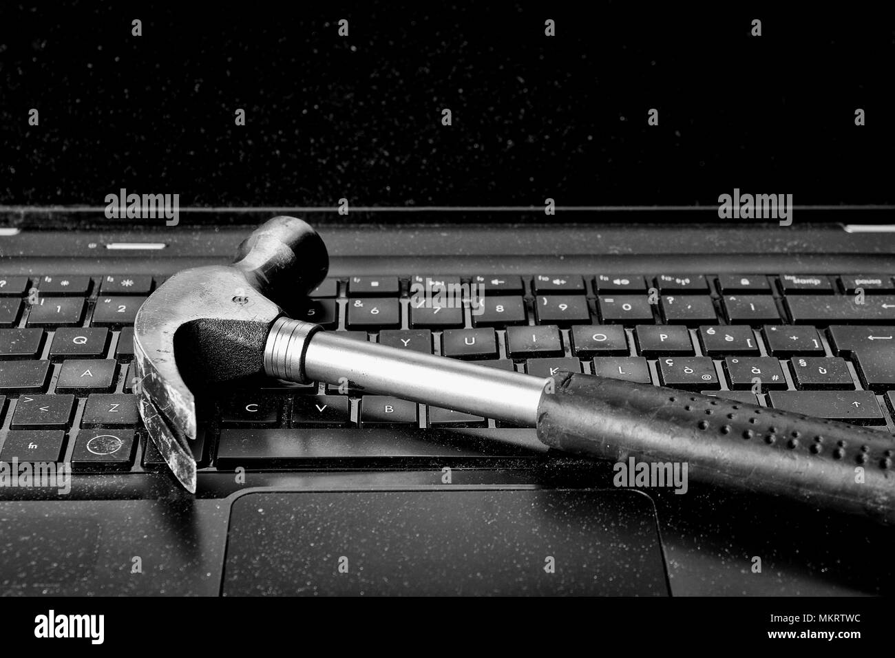 Hammer laying on keyboard of broken laptop Stock Photo