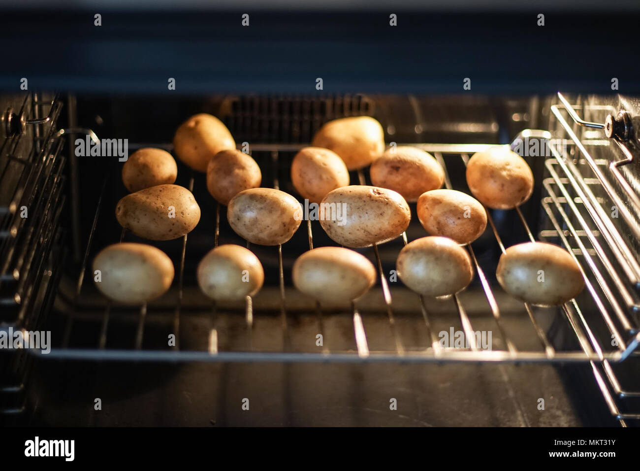 Potatoes in a peel are baked in an oven Stock Photo