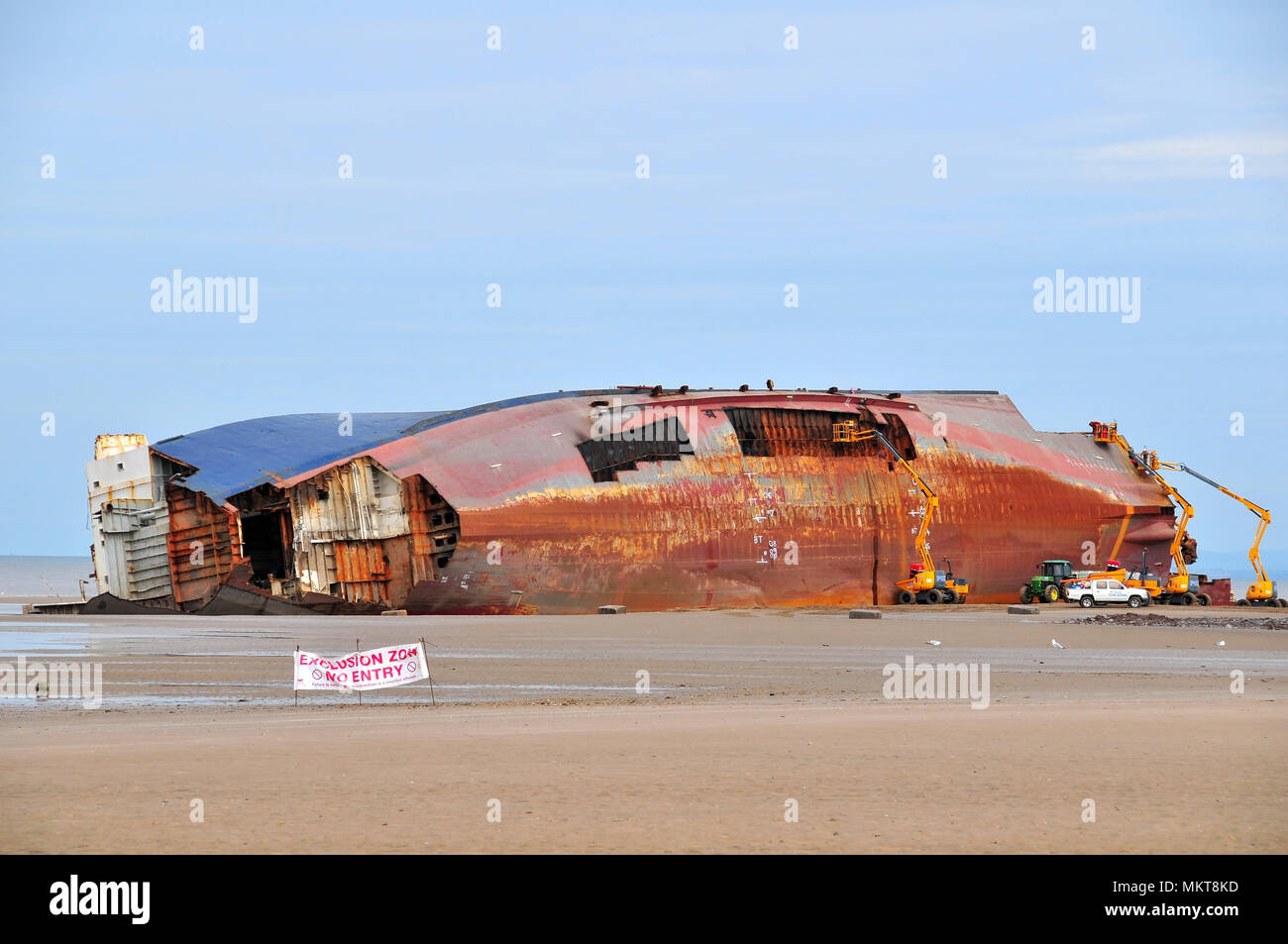 Blue sky view across sand beach with Exclusion Zone sign to Riverdance Ferry wreck, bows, hull plates, propellors removed, Anchorsholme, Cleveleys, UK Stock Photo