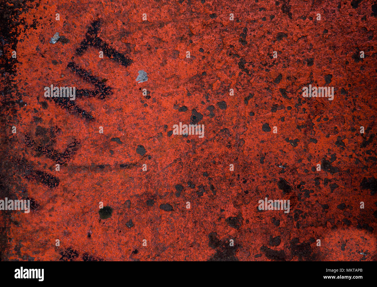 Gritty bright red texture on a rusted metal with the word 'rent' Stock Photo