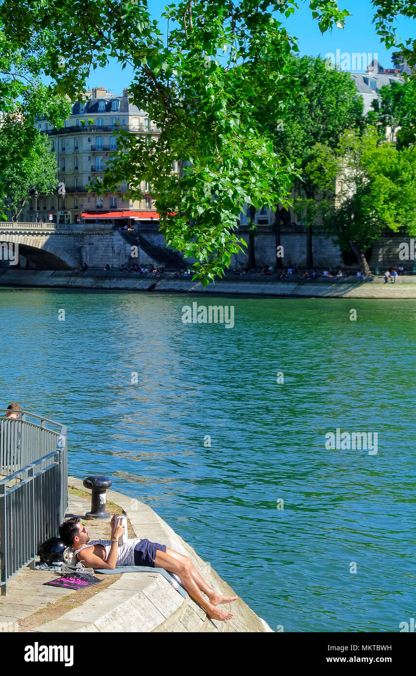 A young french man reading a book, seine river, paris, france Stock Photo