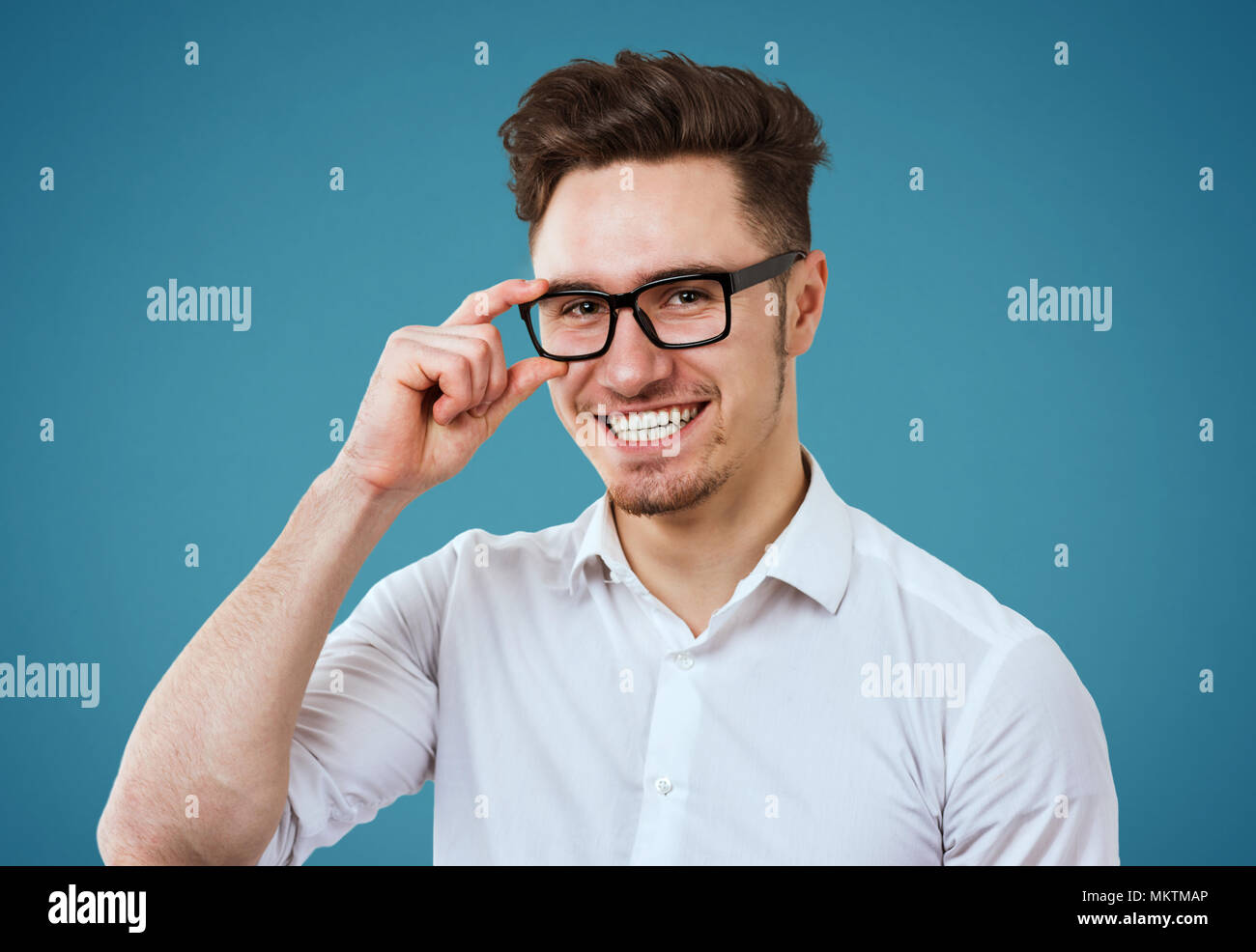 Happy young man wearing white shirt and glasses posing on blue background Stock Photo