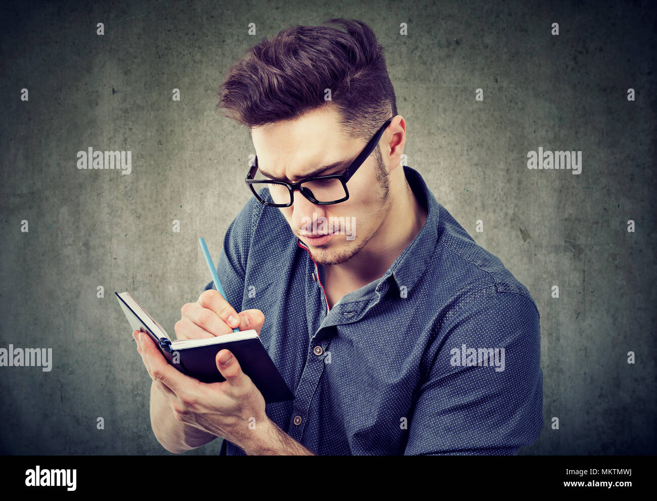 Young handsome man concentrated on planning and organizing life taking notes in pad. Stock Photo