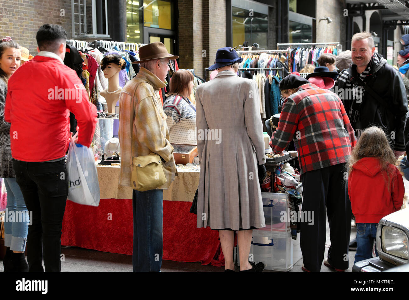 Rear view of couple in 1940s style clothing market stall at the Vintage Car Boot Sale fair at Granary Square in Kings Cross London UK KATHY DEWITT Stock Photo