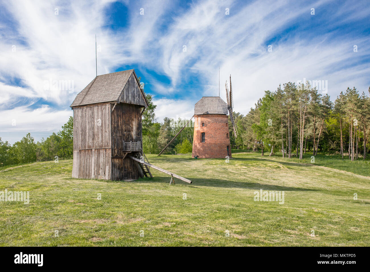 Traditional old polish windmills. Wooden and masonry, Spring, green meadow. Open air museum in Dziekanowice, Lednica lake. Stock Photo