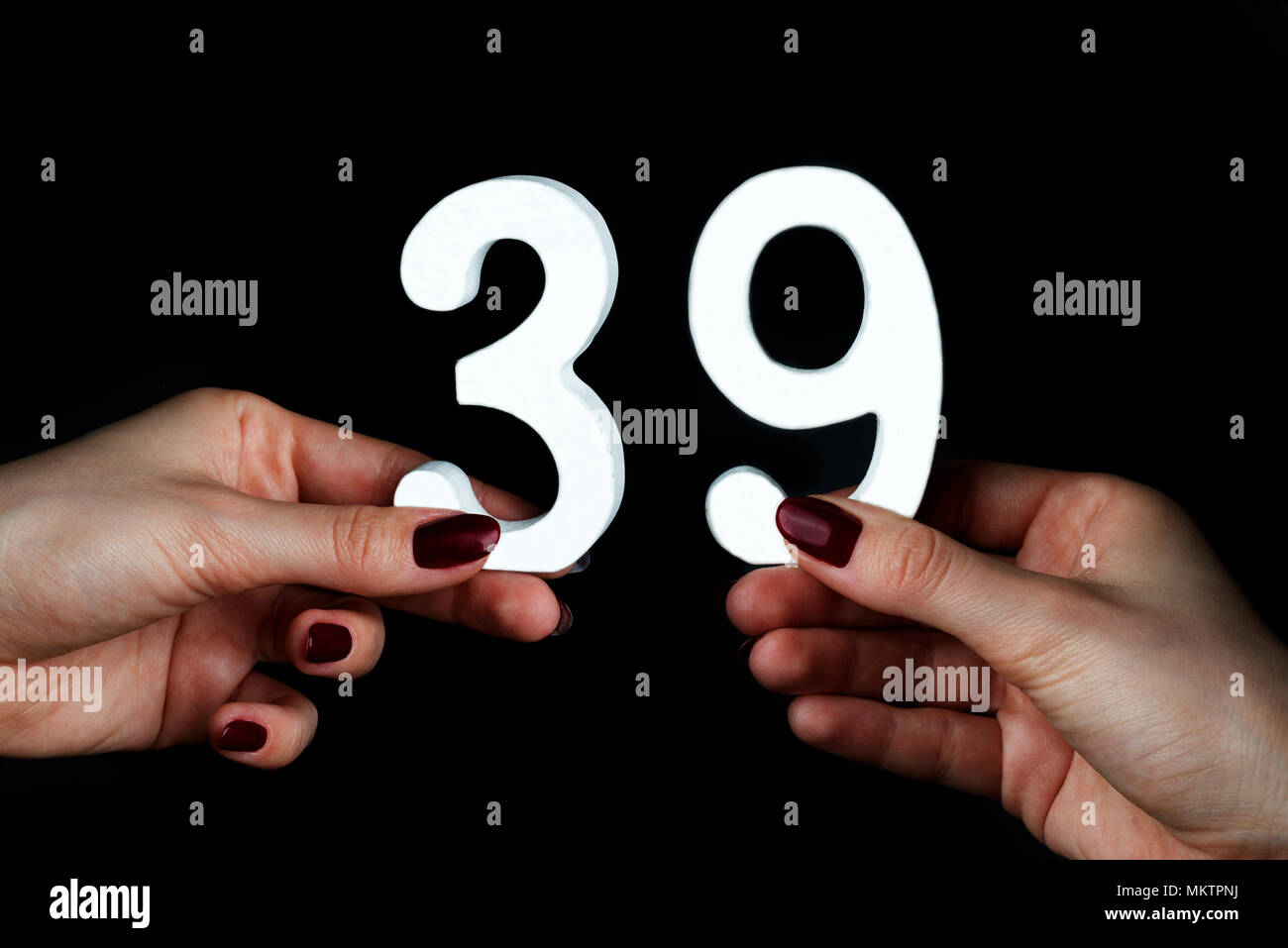 On a black background, female hand with number thirty-nine. Stock Photo