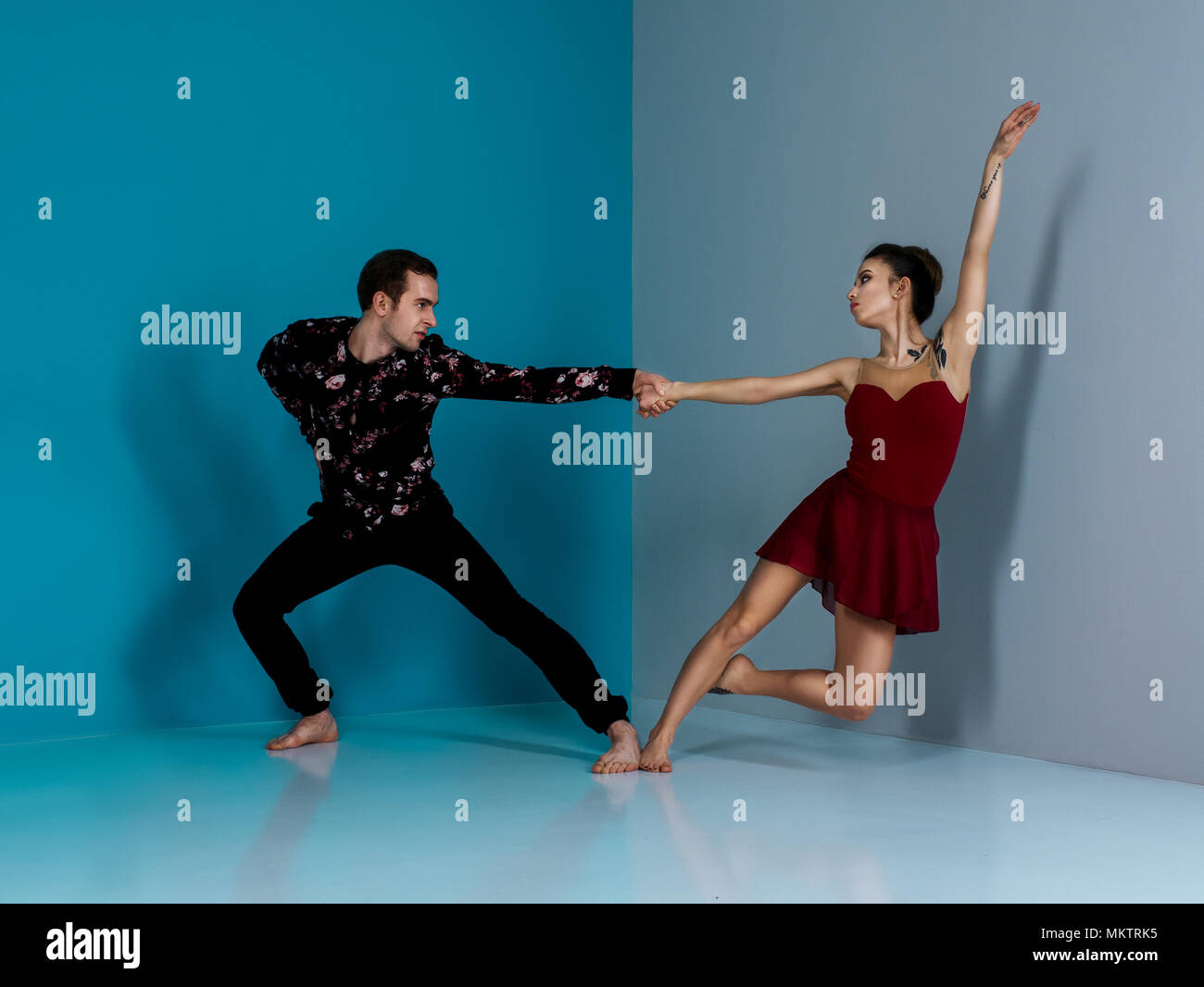 Modern ballet dancer couple in black trousers black in roses shirt and bordo dress performing art dance element with space background Stock Photo