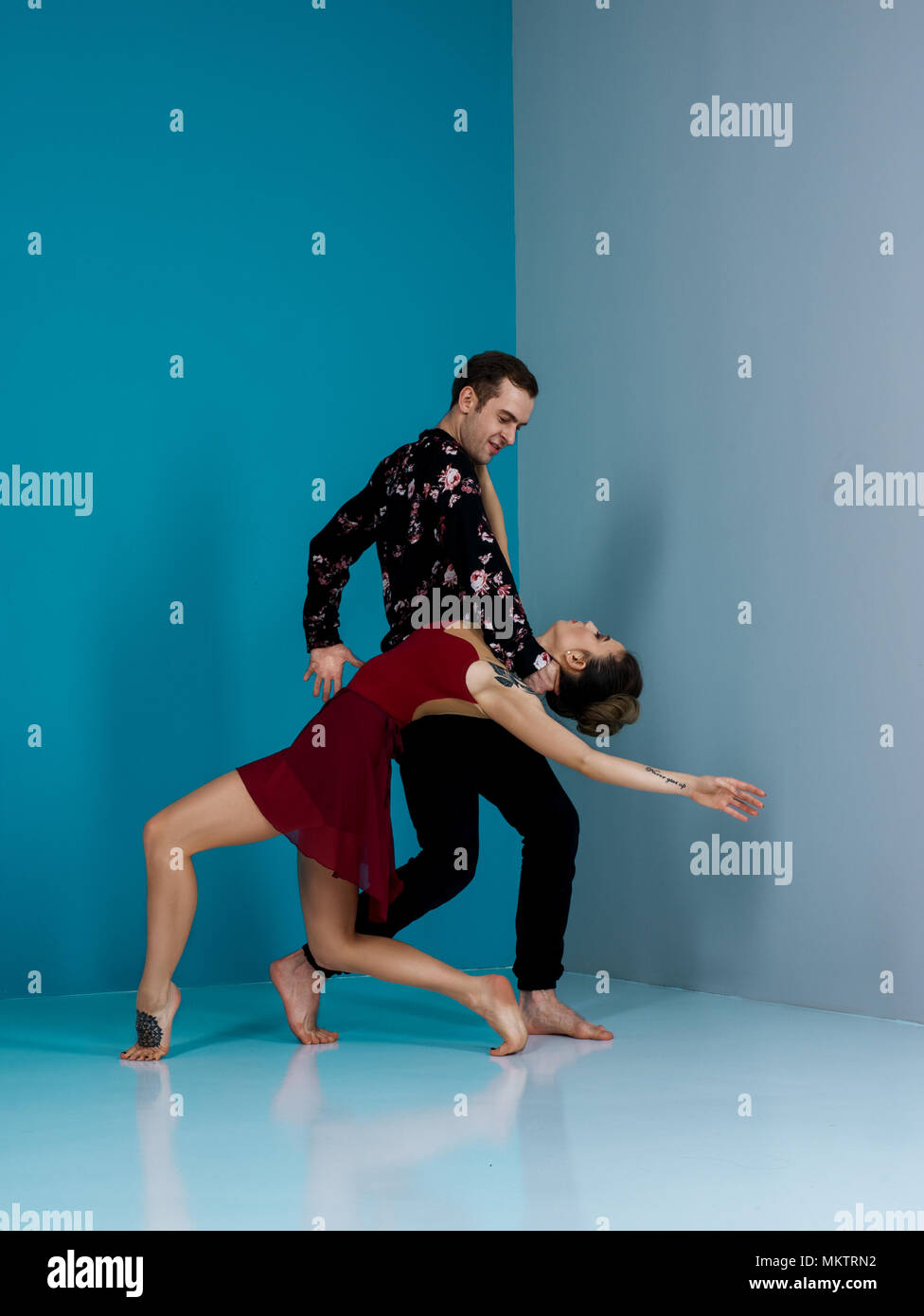 Modern ballet dancer couple in black trousers black in roses shirt and bordo dress performing art dance element with space background Stock Photo