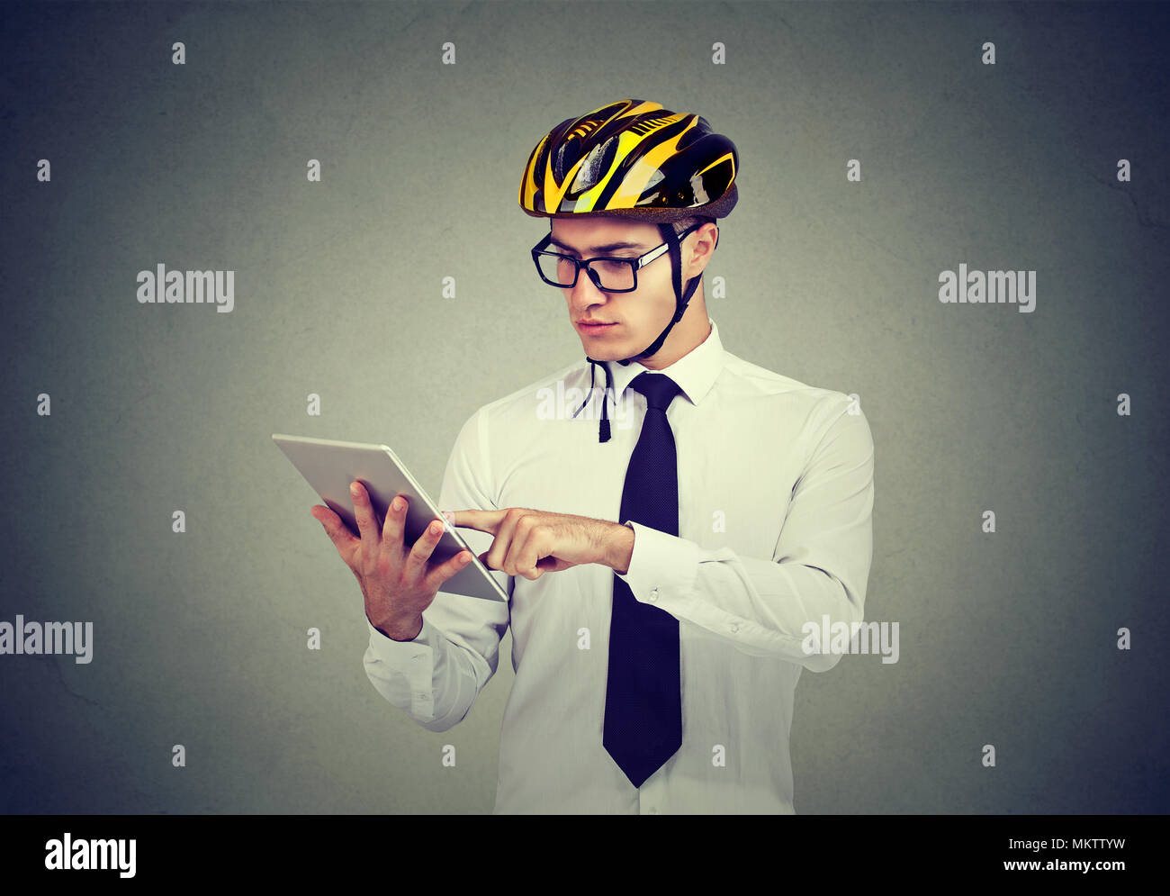 Young cautious man in helmet browsing tablet carrying out business safely. Stock Photo