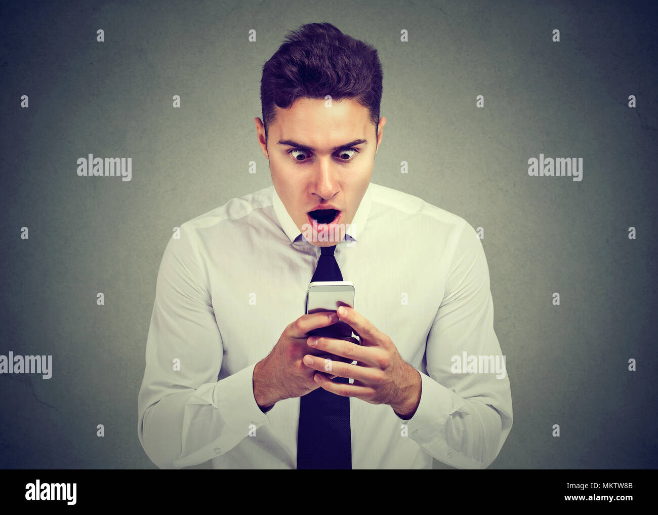 Closeup portrait surprised man looking at phone seeing unexpected news or photos with wonder emotion on face Stock Photo