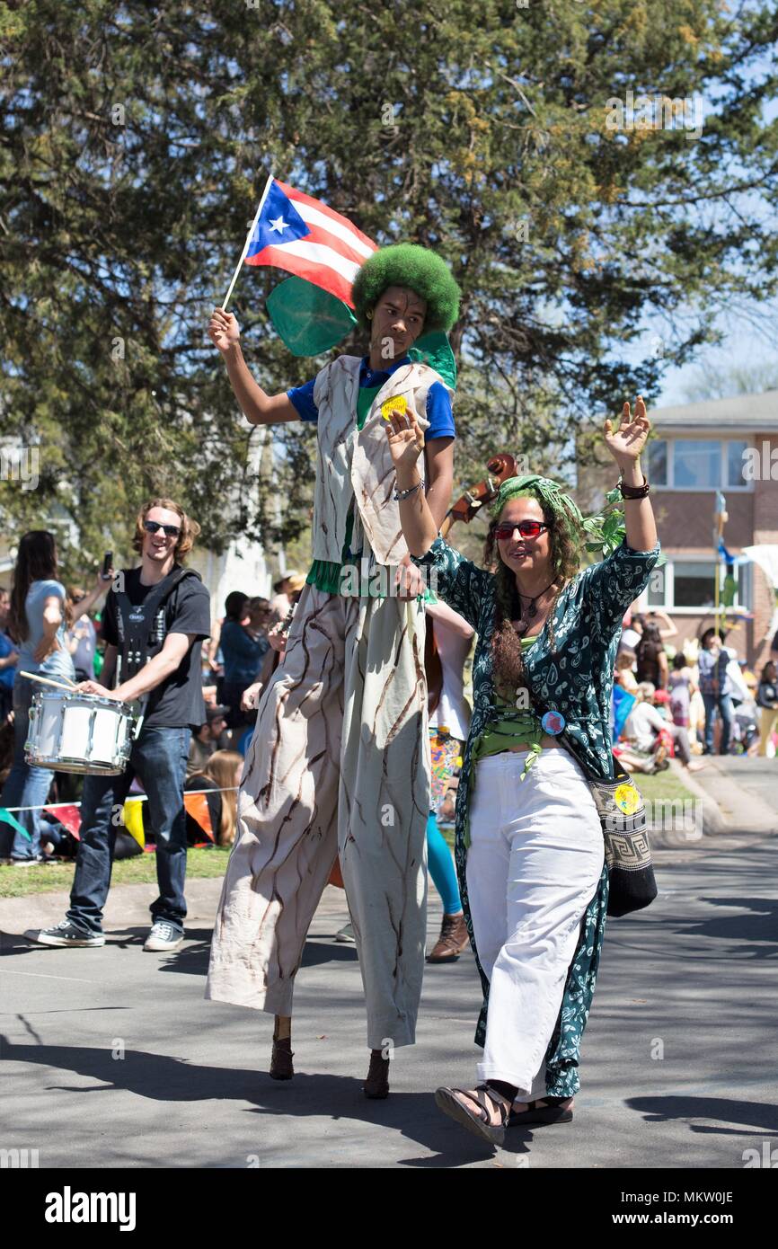 A black man with a green afro walking on stilts at the May Day parade