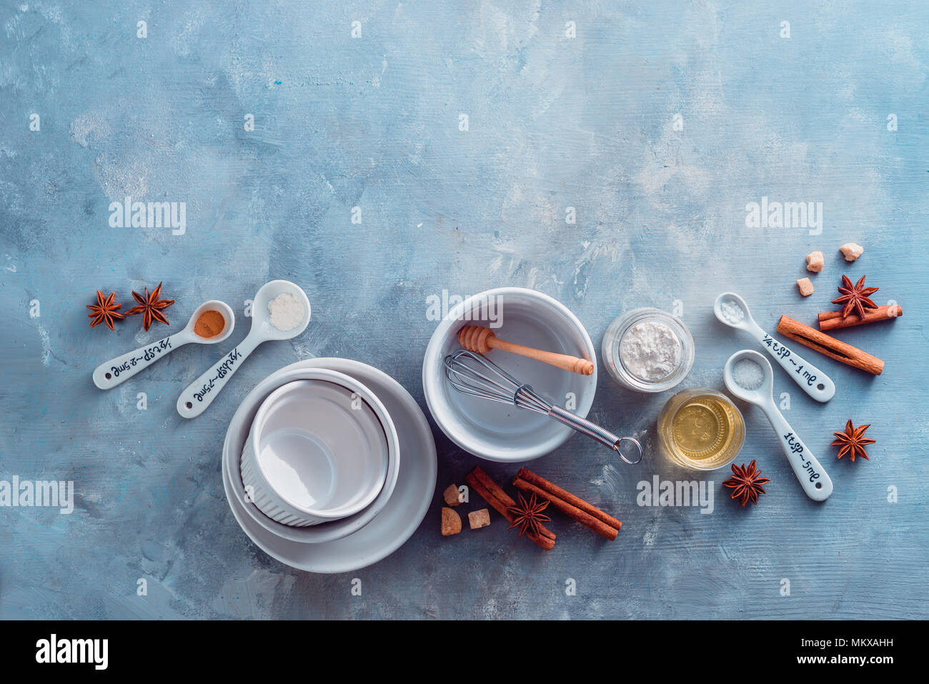 Porcelain baking forms with spoons, flour, sugar and spices on a marble kitchen table. Baking tools and ingredients with copy space. Making pastry con Stock Photo