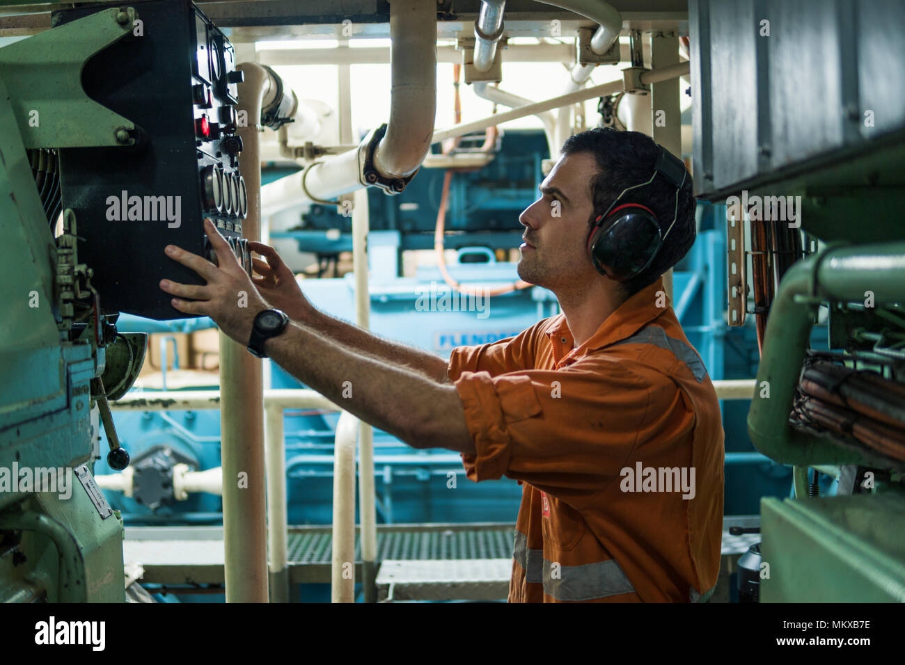 Marine engineer inspecting ship's engine in engine control room Stock