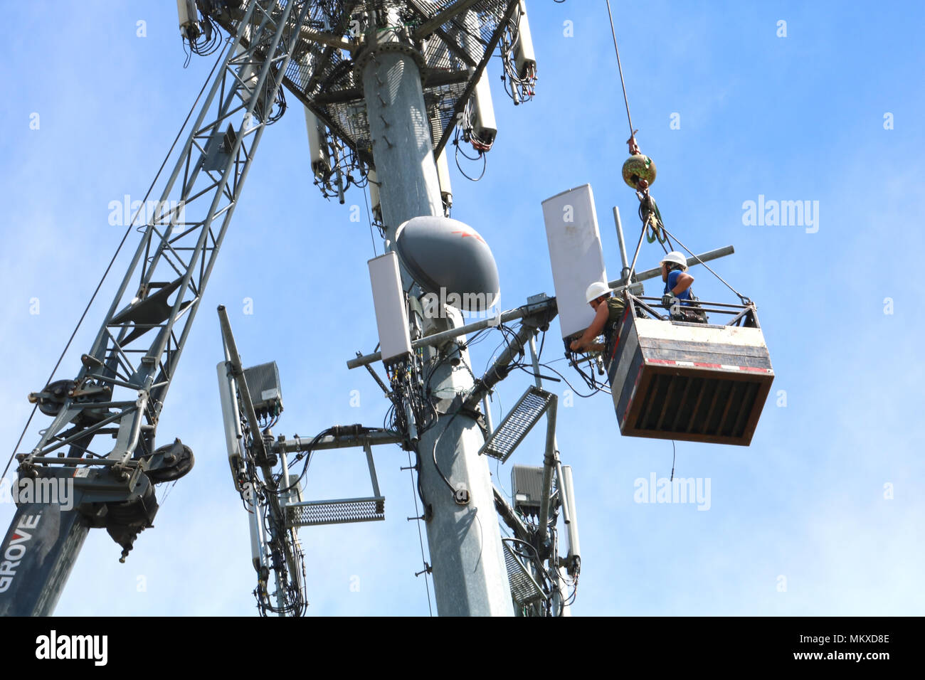Two men suspended in the air via a cable while working on a cellphone tower in Ferndale, Washington, USA. Stock Photo