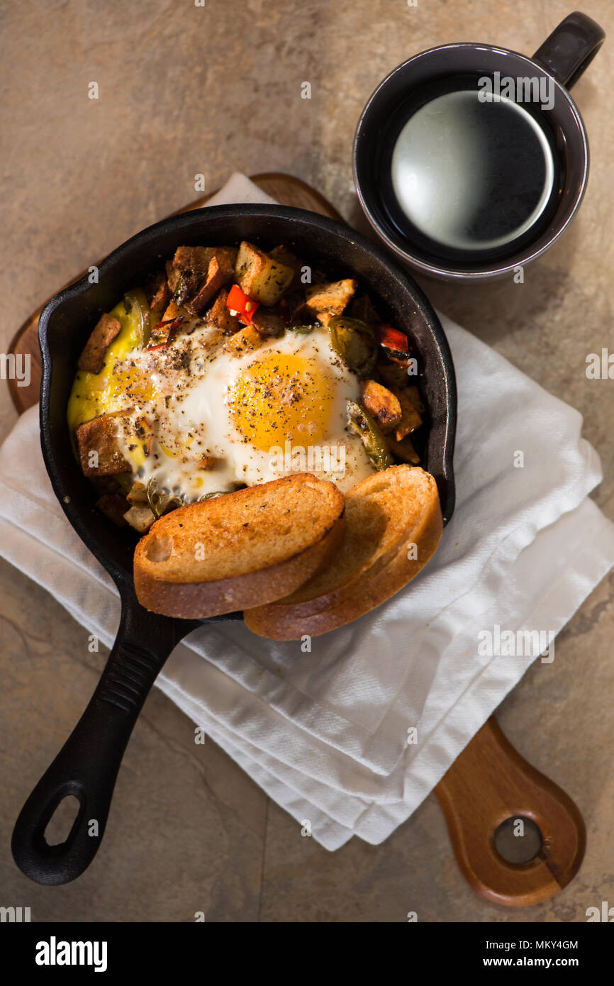 Breakfrast hash in cast iron skillet with sunny side up fried eggs, ham