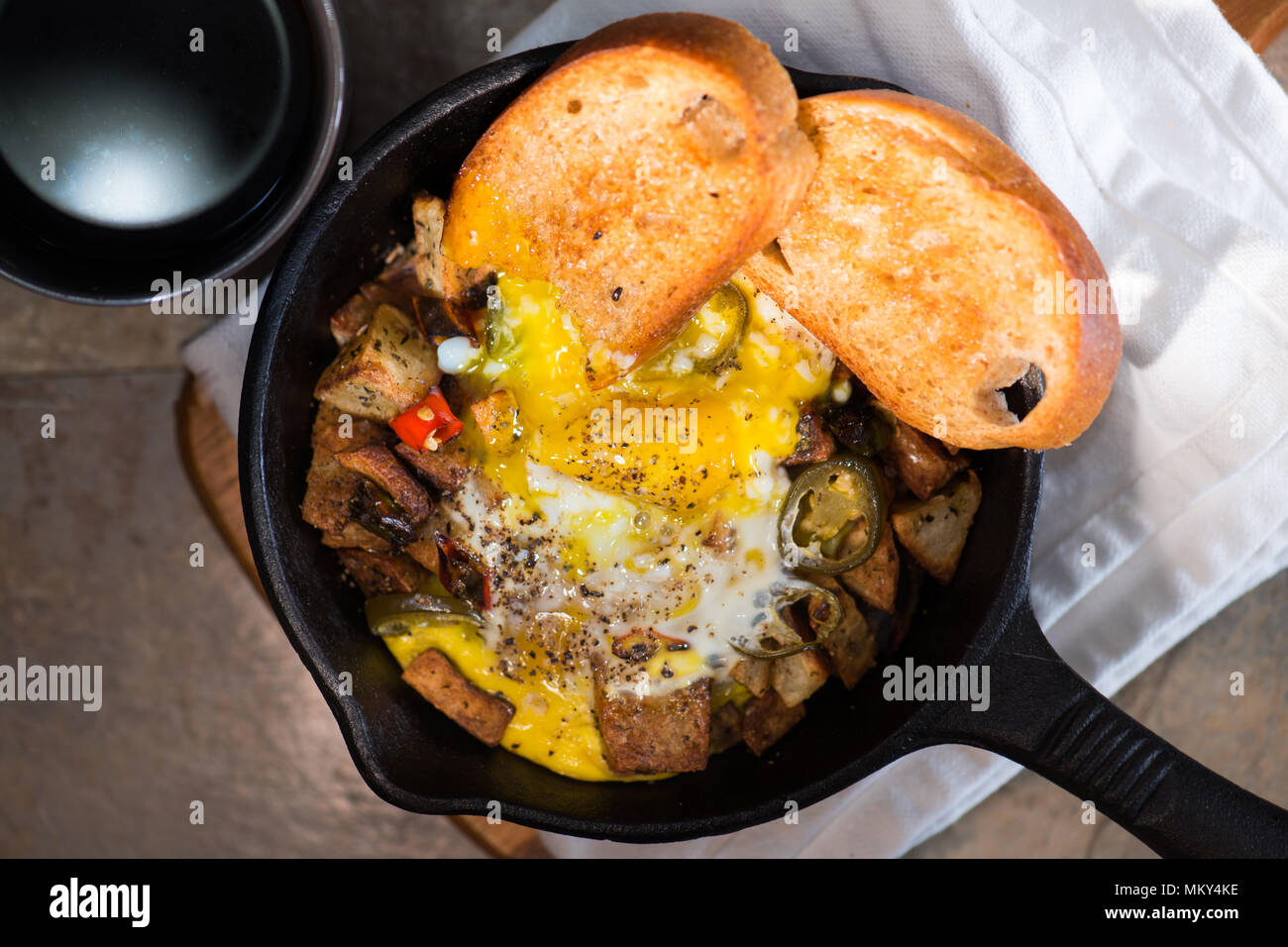 Breakfrast hash in cast iron skillet with sunny side up fried eggs, ham