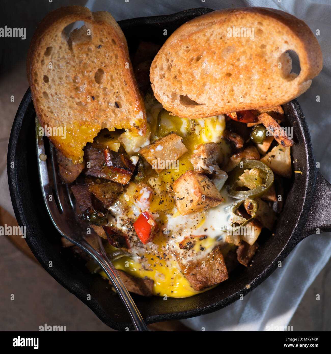 Breakfrast hash in cast iron skillet with sunny side up fried eggs, ham
