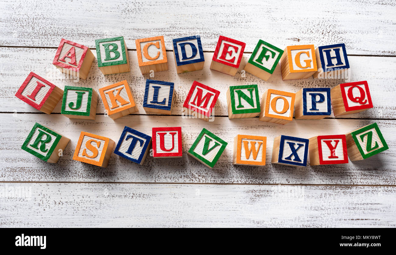 Multi-colored wooden letter blocks making the alphabet on white wood  background Stock Photo - Alamy