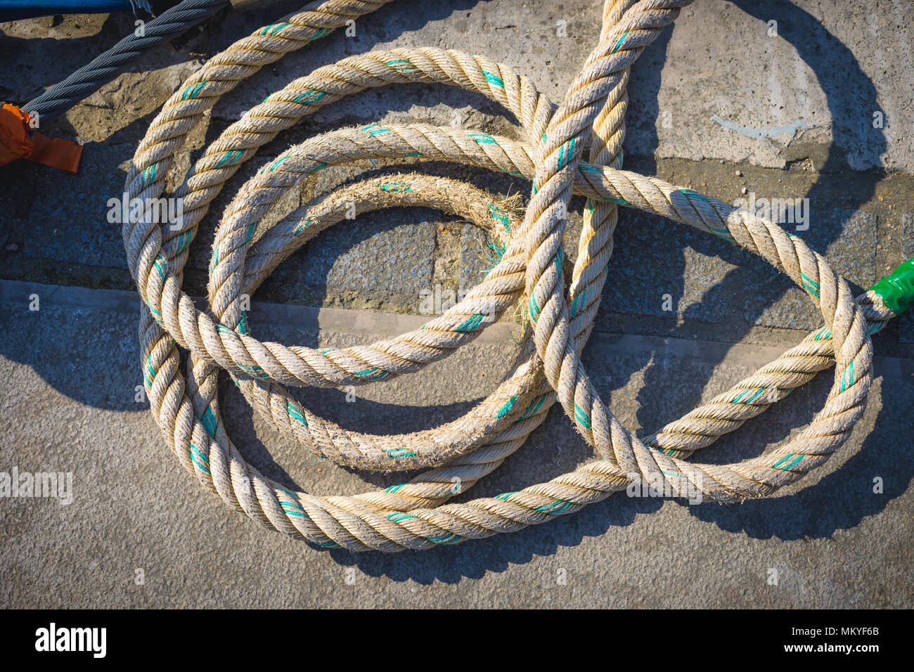 Marine rope lying on the sidewalk near the pier. Stock Photo