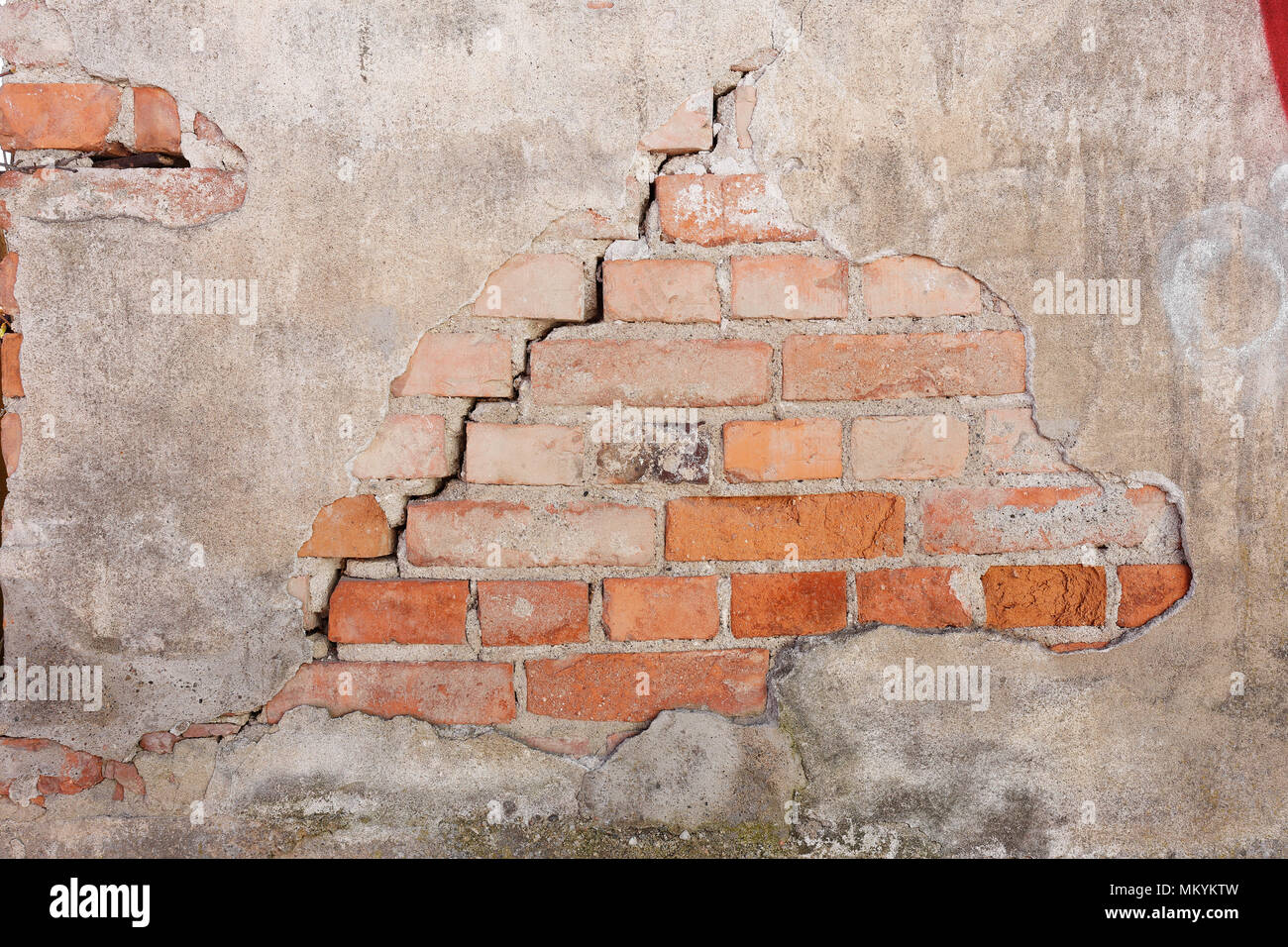 Brick wall in need of repairs with crack and damaged plaster. Stock Photo