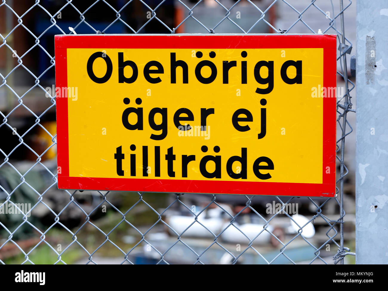 Close up of yellow sign on a fence with text in Swedish No admission for unauthorized (Obehoriga ager ej tilltrade) Stock Photo