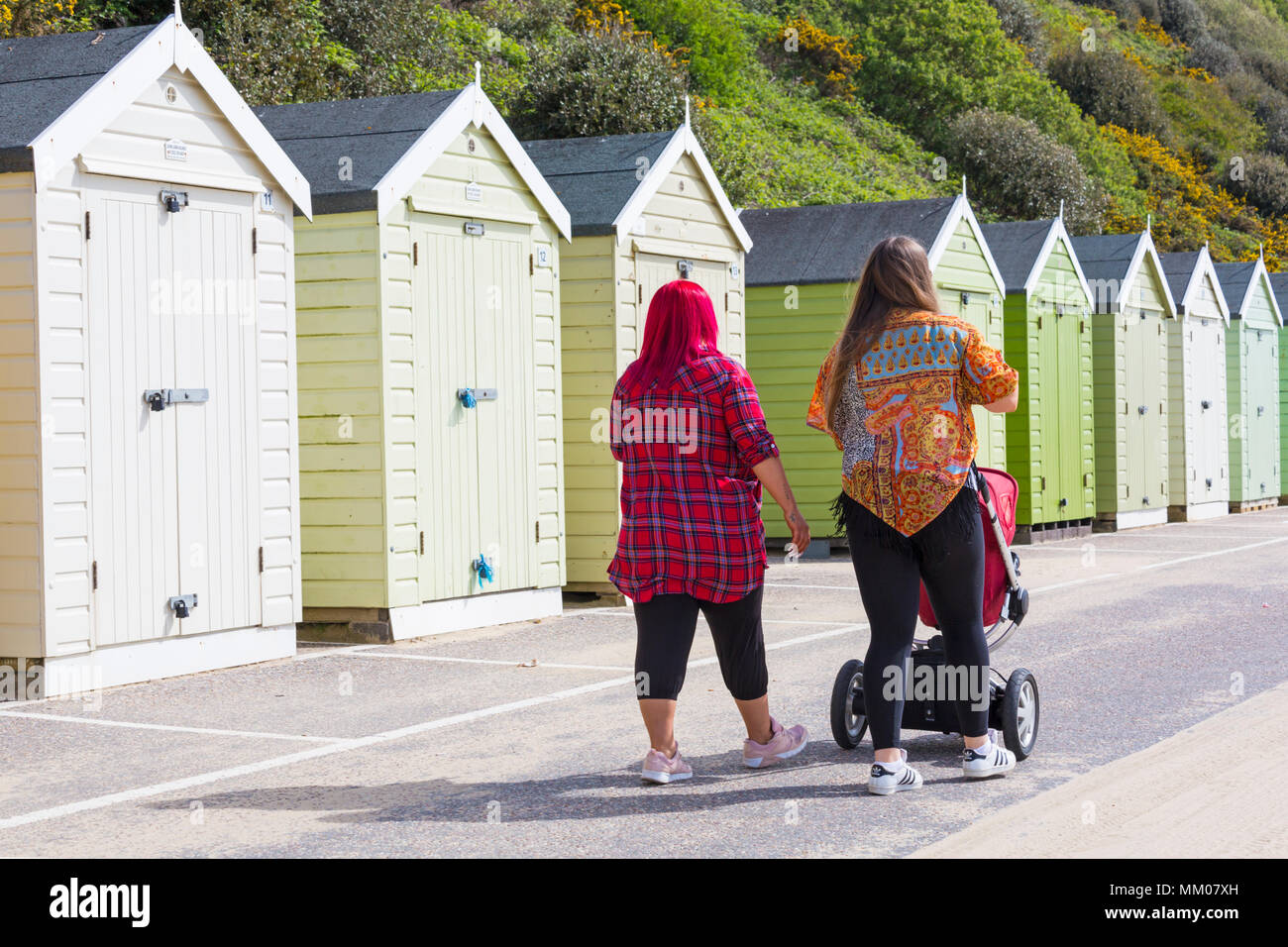 Bournemouth, Dorset, UK. 9th May 2018. UK weather: the sun is still shining! Another warm sunny start to the day, as visitors head to the beach before the weather changes. Colourful women strolling past beach huts! Stock Photo