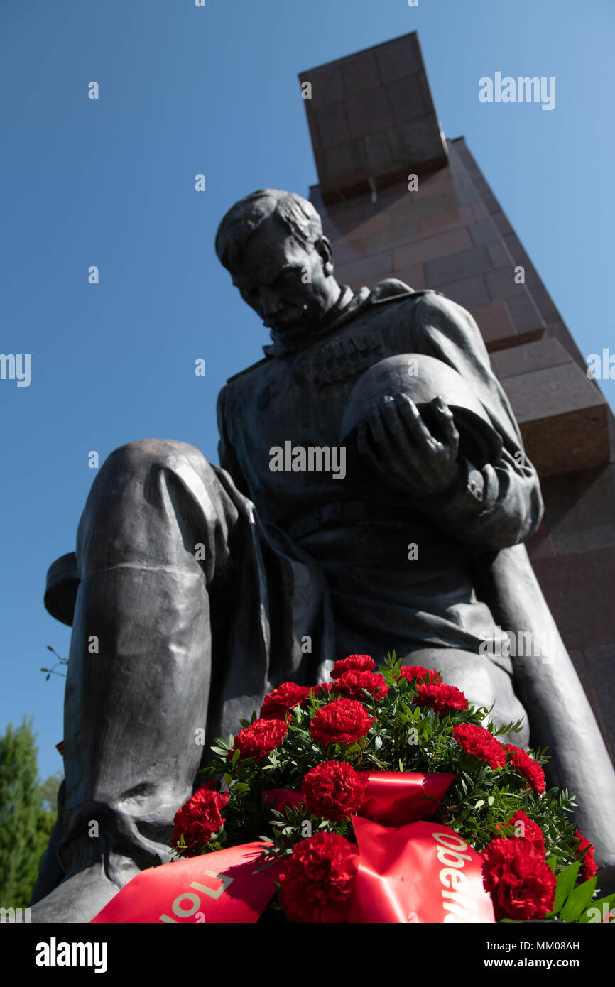 09 May 2018, Germany, Berlin Red carnations lying by a statue on the