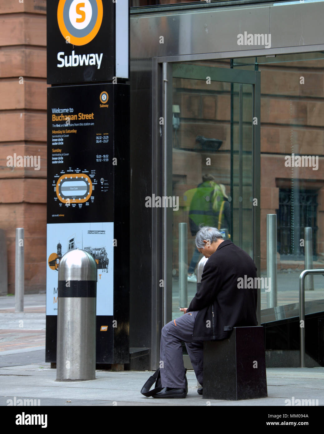 Glasgow, Scotland, UK 9th May. UK Weather : Chinese man sitting on bench mobile smart phone. Buchanan subway at the heart of the city offers little for the tourist as dull wet weather pervades after the hot Bank Holiday.. Gerard Ferry/Alamy news Stock Photo