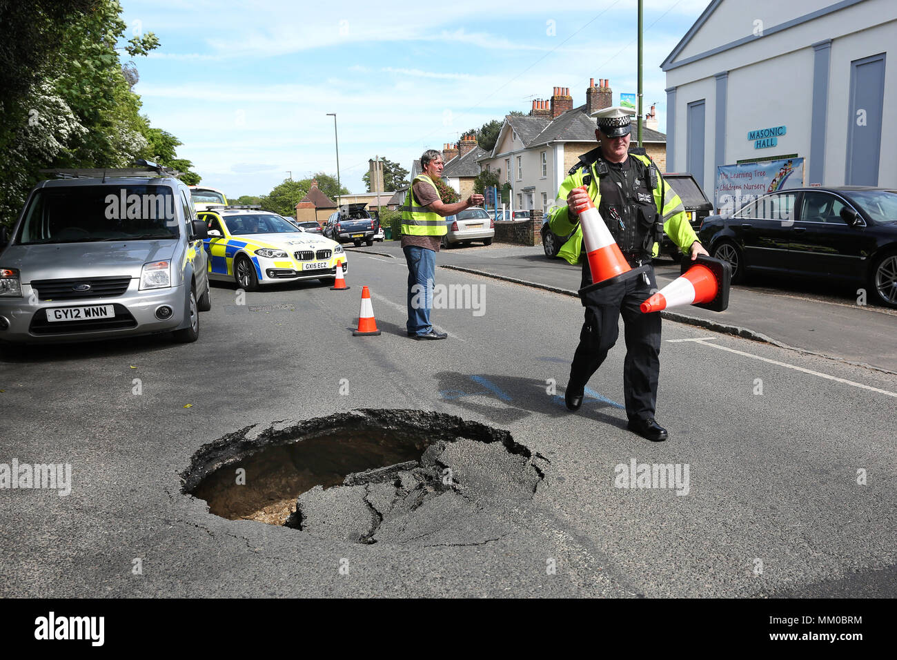 Midhurst, Near Chichester, West Sussex, UK. A huge sink hole pictured on Bepton Road, close to the high street and causing long delays. Members of the public directed traffic for over 45minutes until police arrived to close the road.  Wednesday 9th May 2018 © Sam Stephenson/Alamy Live News. Stock Photo