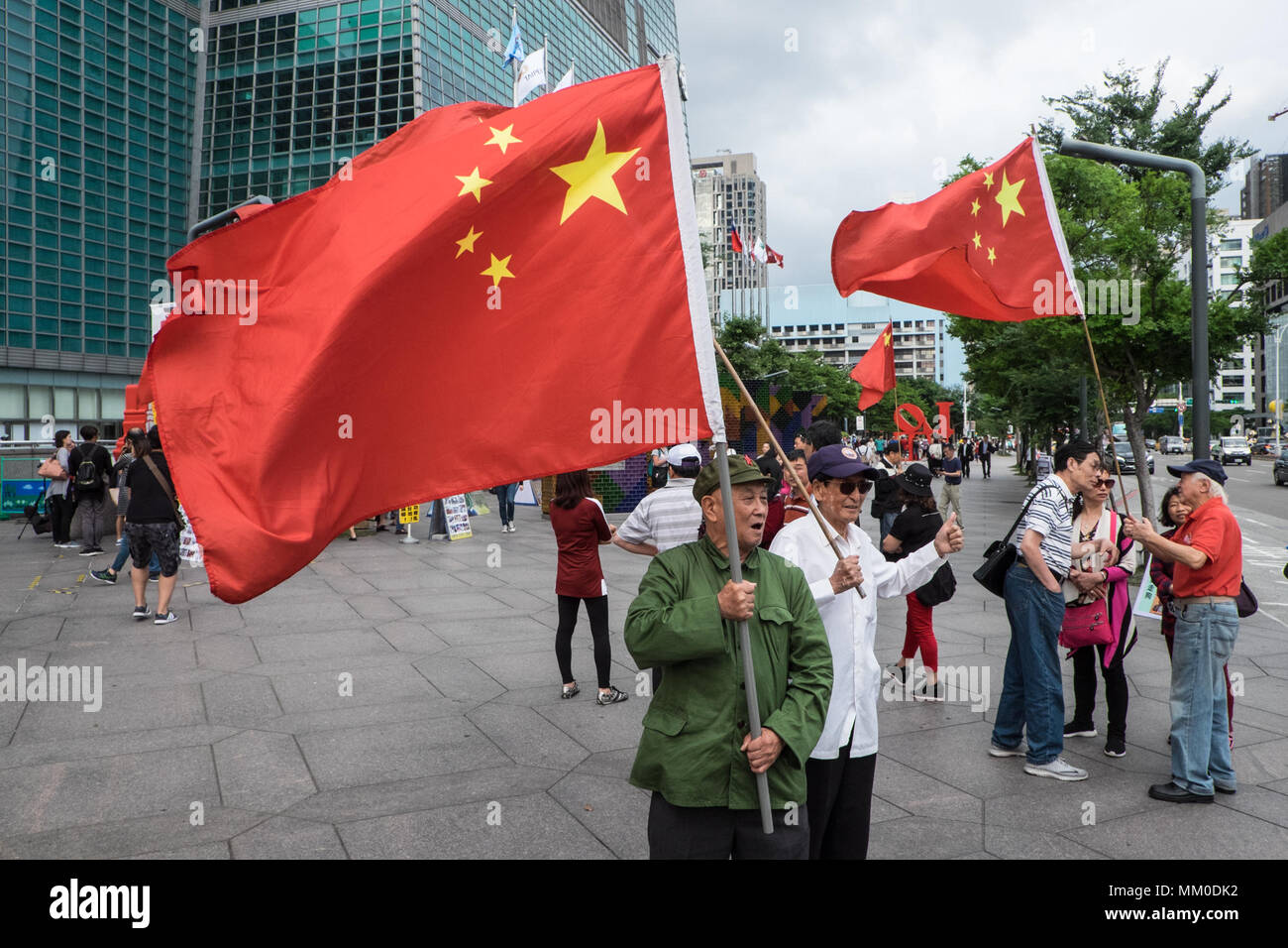 Mainland Chinese tour groups at the base of Taipei 101 Tower,attract two demonstrations,Taipei,Taiwan,Asia.The mainland Chinese tour buses park infront of Taipei 101 Tower,the second tallest building in the world,for the mainland Chinese to access this tourist attraction. On disembarking and getting on the buses nationalist Chinese supporters welcome them flying the Chinese flag.The pro-China supporters are there as a counter-demonstration to another group of demonstrators,the Falun Dafa/Falun Gong that have placards protesting about the persecution of members of the banned organization within Stock Photo