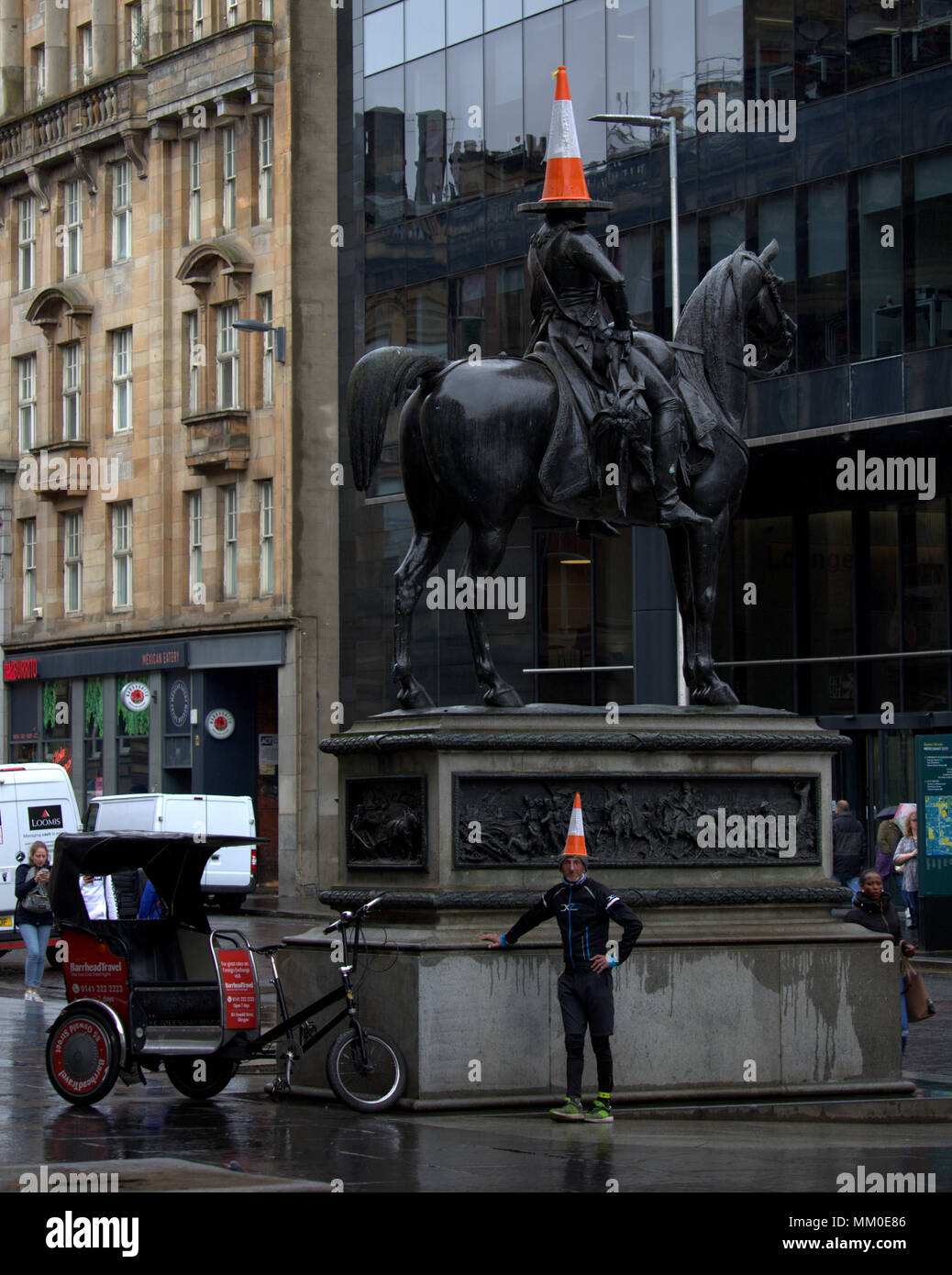 Glasgow, Scotland, UK 9th May. Glasgow, Scotland, UK 9th May. traffic cone  Royal Exchange Square  Duke of Wellington statue. The Cone headed man at the city’s goma museum of modern art is a tourist icon as is Glasgow.s only full time day bike taxi for tourists and locals alike Tom Brown and his  cycle rickshaw in  the heart of the city  as dull wet weather pervades after the hot Bank Holiday.. Gerard .. Gerard Ferry/Alamy news Stock Photo
