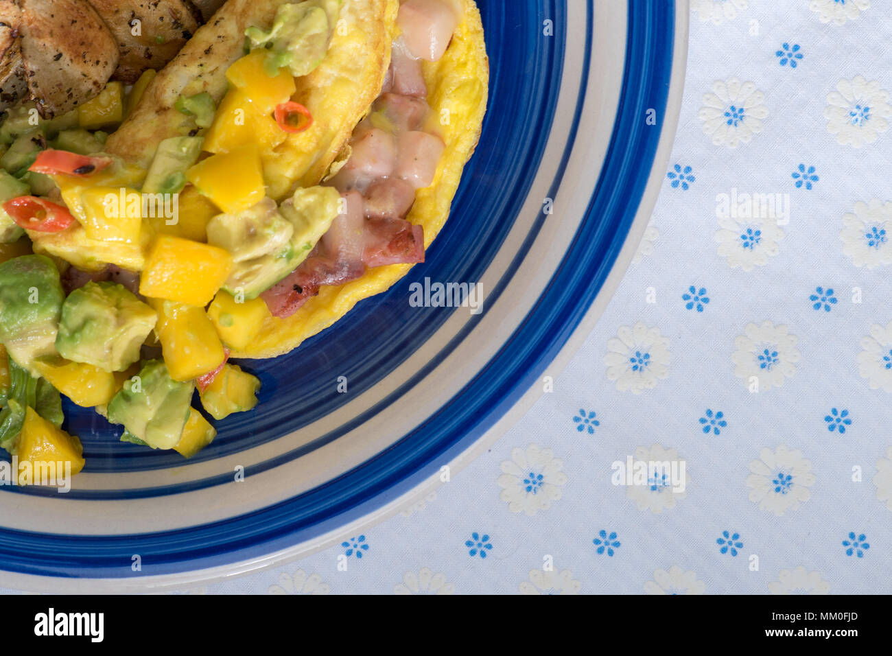 Ham and swiss cheese omelette with spicy mango and avacado salsa and pan fried hashbrown potatoes Stock Photo