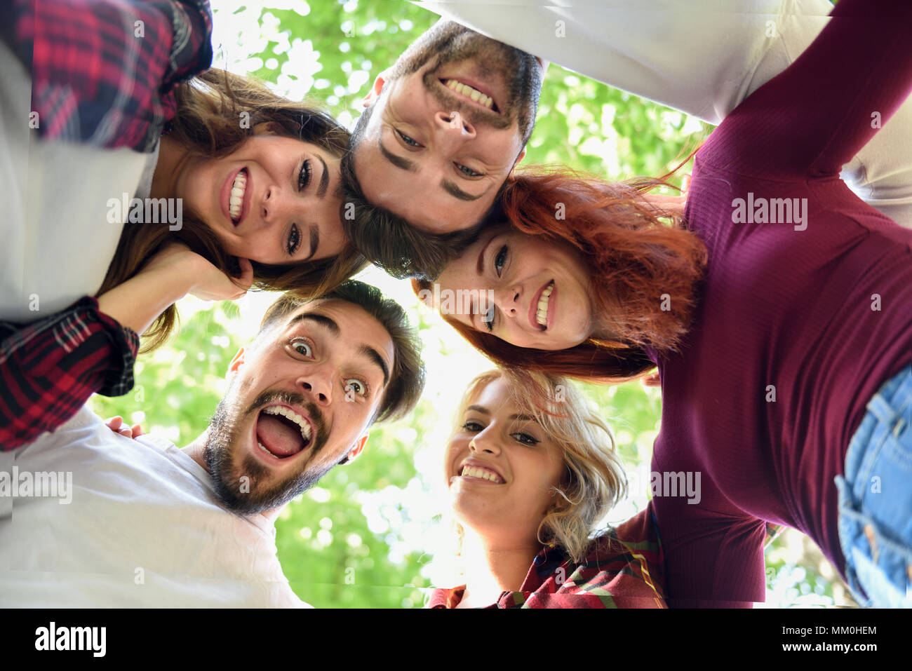 Group of young people together outdoors in urban background. Men and women looking down Stock Photo