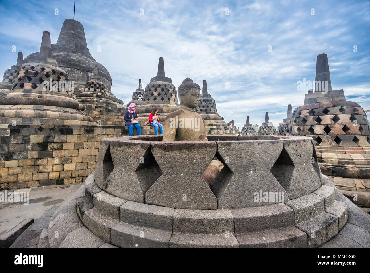 an exposed Buddha statue in an opened perforated stupa on the circular top terrace of 9th century Borobudur Buddhist temple gazes serenly over the Ked Stock Photo