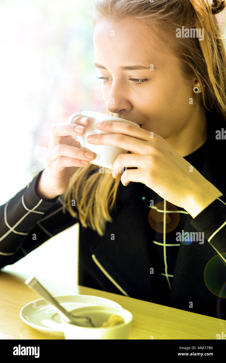 Girl nice appearance, drink a drink (tea, coffee, milk) from a white Cup. Stock Photo