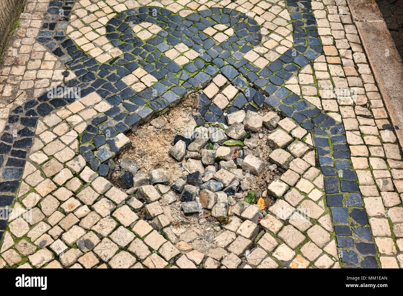 A section of Portuguese Pavement in Lisbon, Portugal, with a pot hole in it. Stock Photo