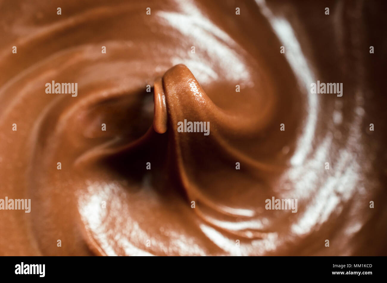 Close up (macro) of melting milk chocolate, stirred into swirls with rising peak in middle of frame. Shallow depth of field. Stock Photo