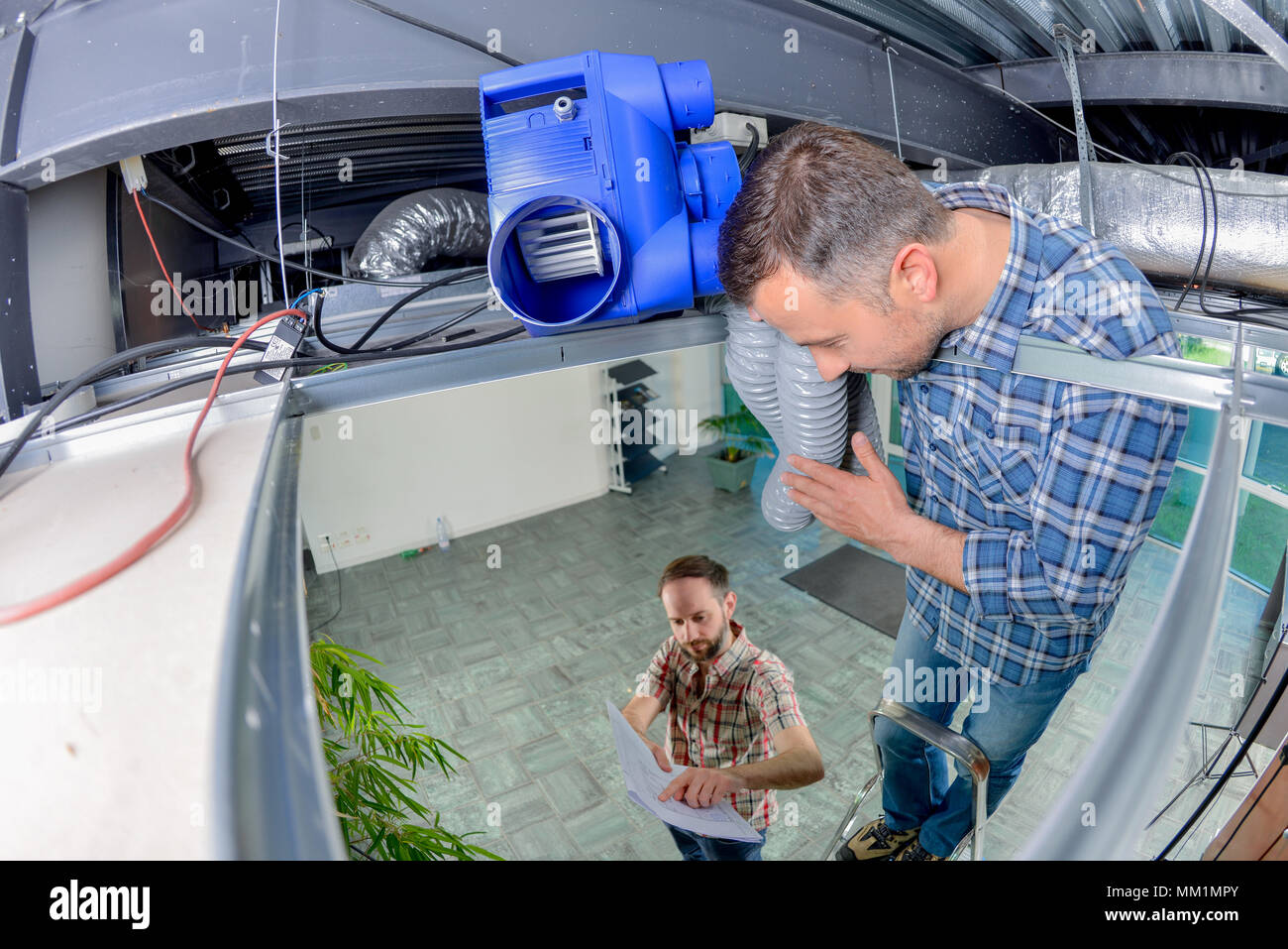Two electrician working in a ceiling panel Stock Photo