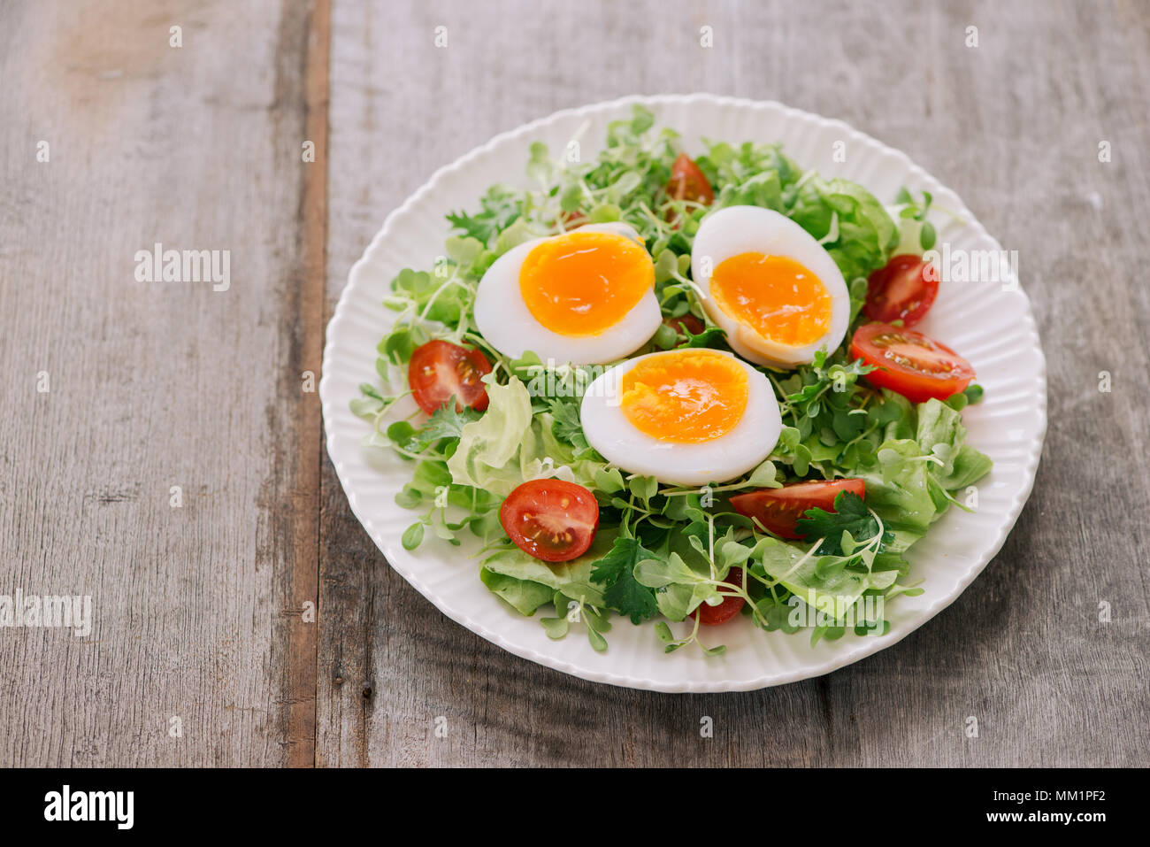 Lambs lettuce salad, hard-boiled eggs, tomatoes and honey mustard dressing Stock Photo