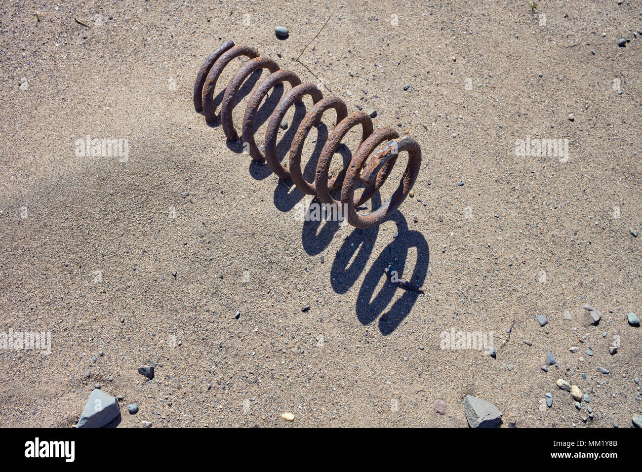 Rusted car spring half hidden by sand on a beach at Blue Point, Isle of Man Stock Photo