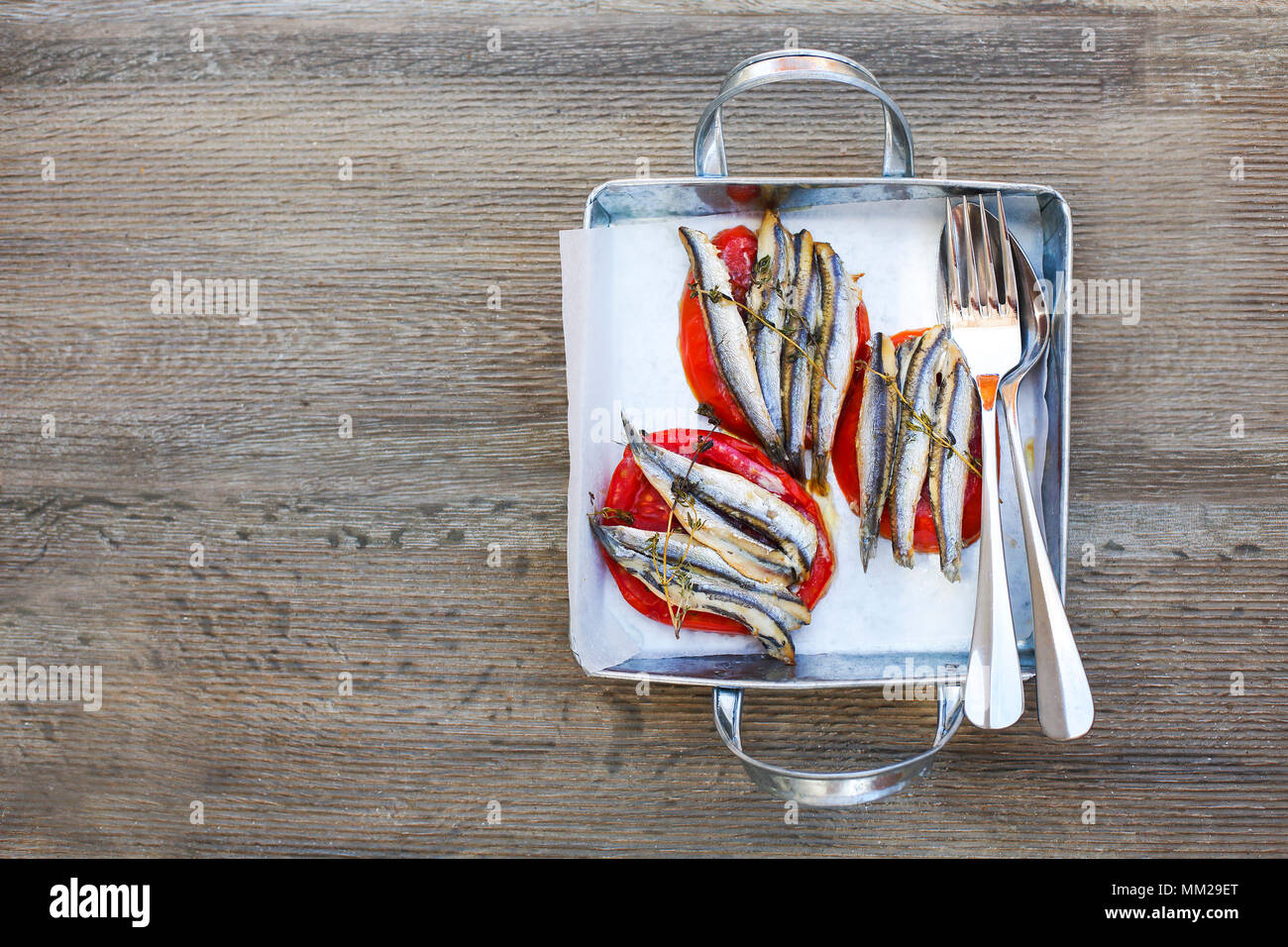 Grilled sardines and tomato on silver metal pan. Greek starter Stock Photo