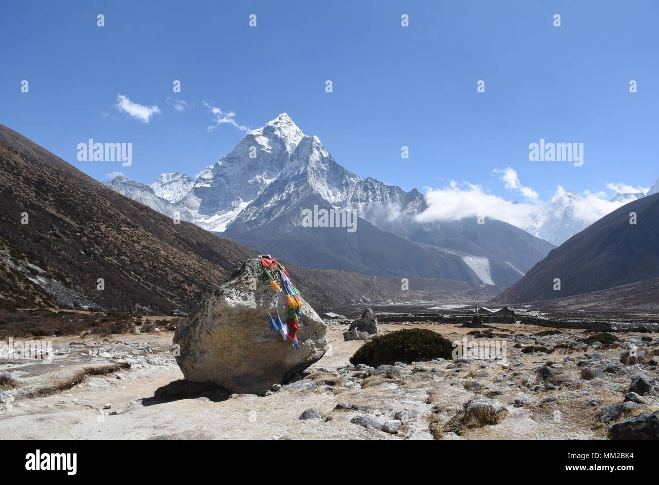 Big stone with praying flags on the EBC Trek and Mount Ama Dablam in the background Stock Photo