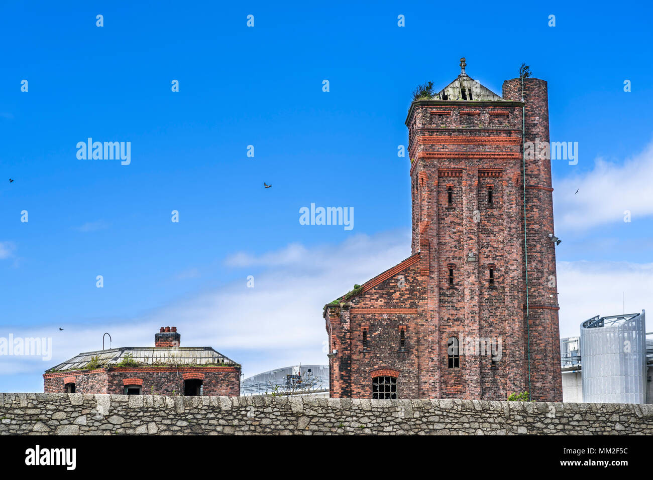 Historic Grade II listed abandoned hydraulic accumulator tower Engine House at Bramley Moore Dock, with modern buildings at Wellington Dock, Regent Ro Stock Photo