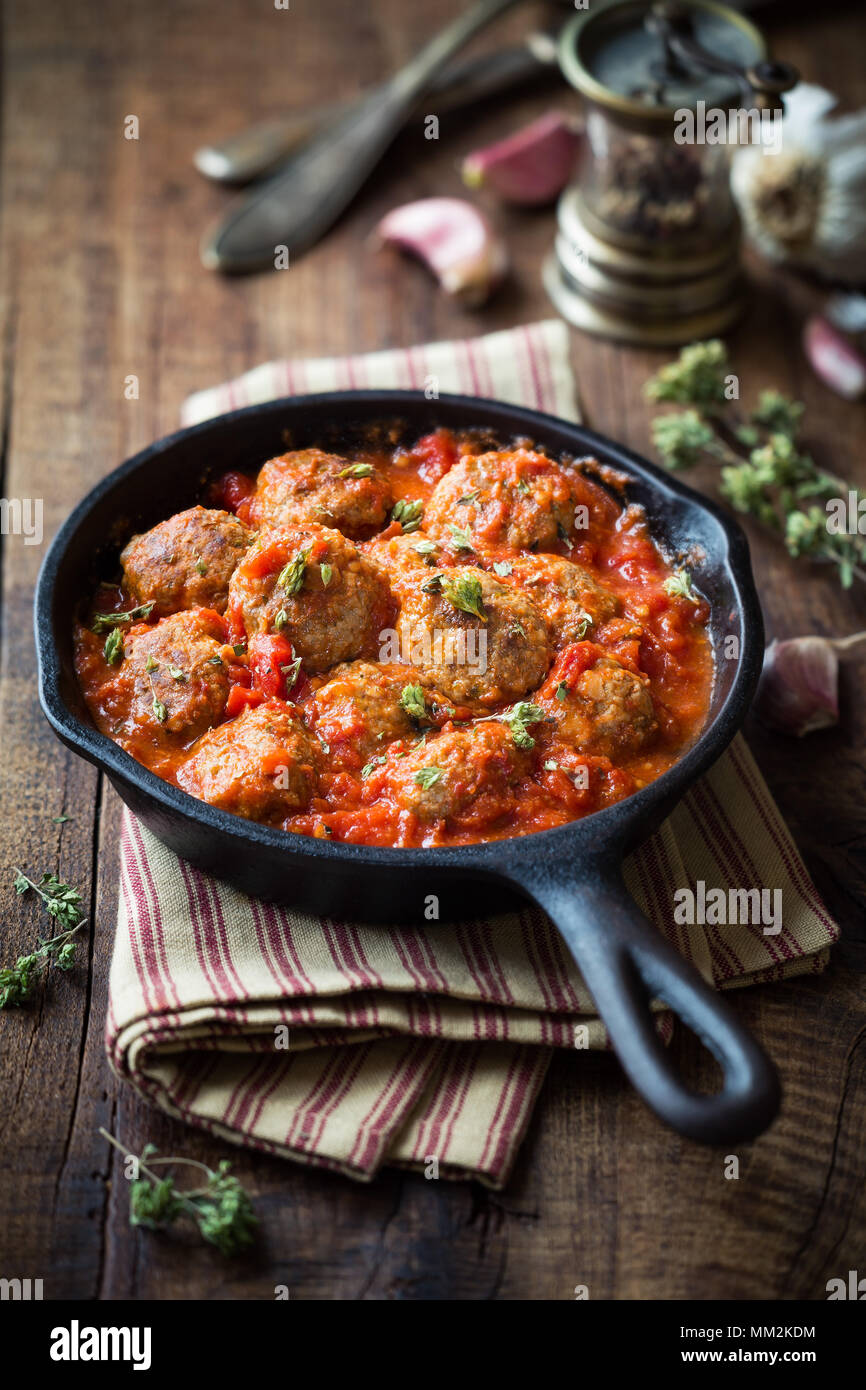 Meatballs in tomato sauce with dried oregano in a rustic vintage cast iron skillet Stock Photo