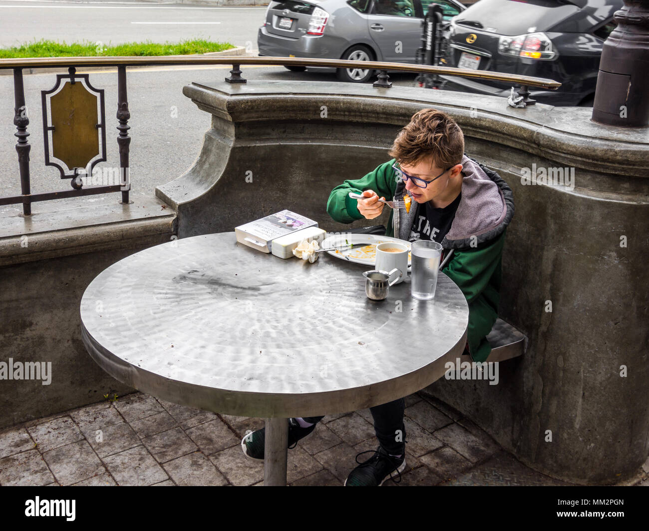 Youth eating alone at outside table, Berkeley, California, USA. Stock Photo