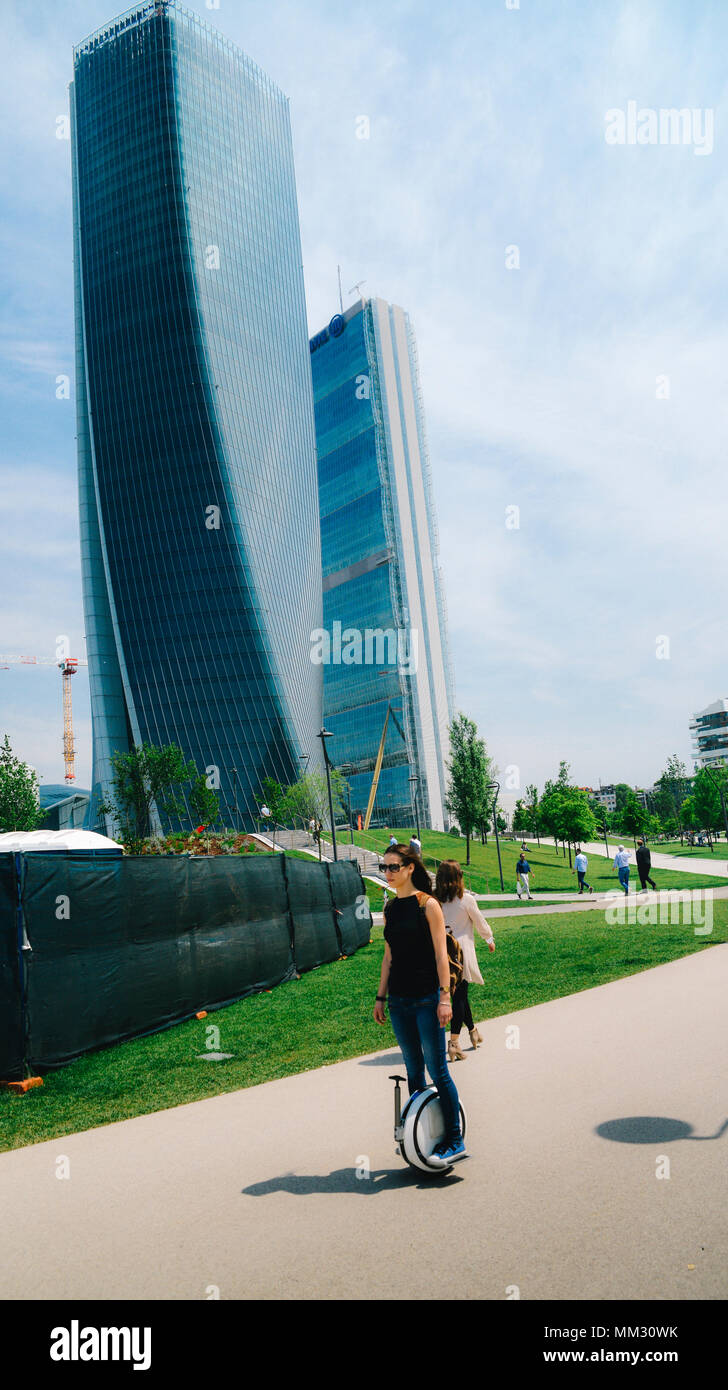 A young woman rides an electric unicycle at Milan's CityLife district park Stock Photo