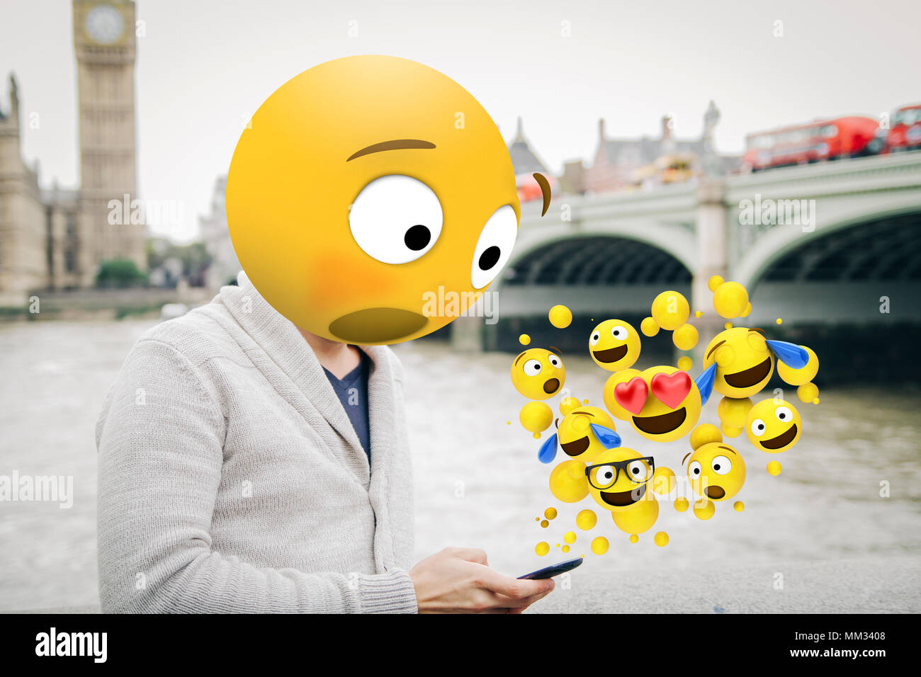 man with emoji head surprised looking at the smartphone al london city Stock Photo